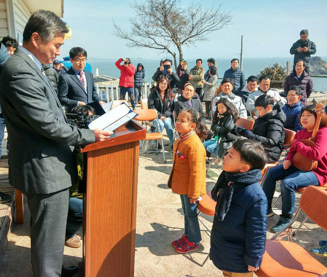 Hiệu trưởng Trường tiểu học Cheongpa, ông Lee Min-cheol, trao giấy nhập học cho cậu bé Ryu Chan-hee (bên phải) và cho một cô bé khác vào học điểm trường khác trên đảo Hodo tại buổi lễ nhập học ngày 3/3/2017. (Ảnh:Hankook Ilbo)